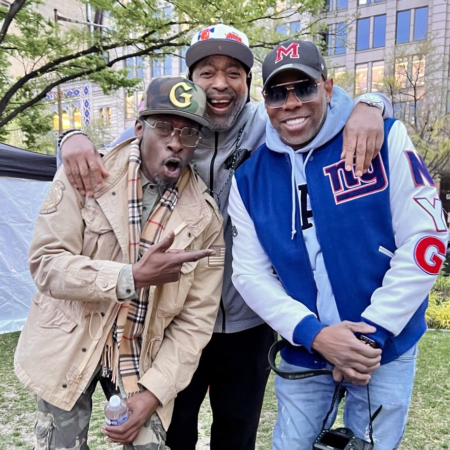 Three men posing together backstage in the park