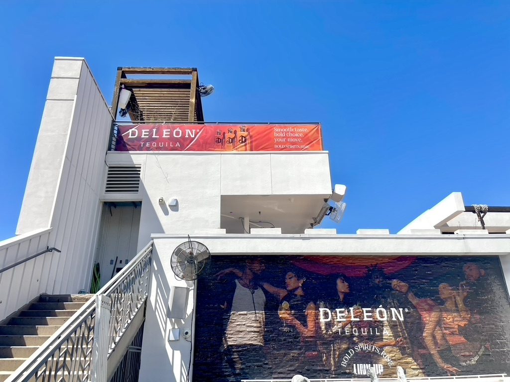 DeLeón Tequila banner and mural on the venue exterior under a blue sky