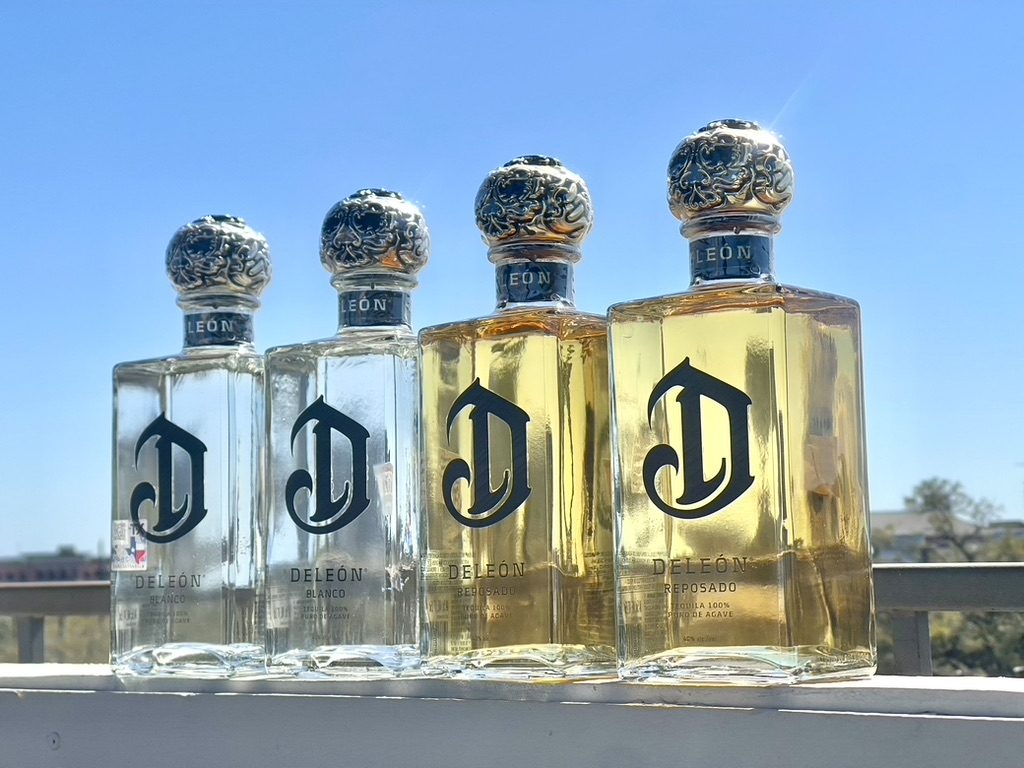 Four DeLeón Tequila bottles lined up on a rooftop ledge