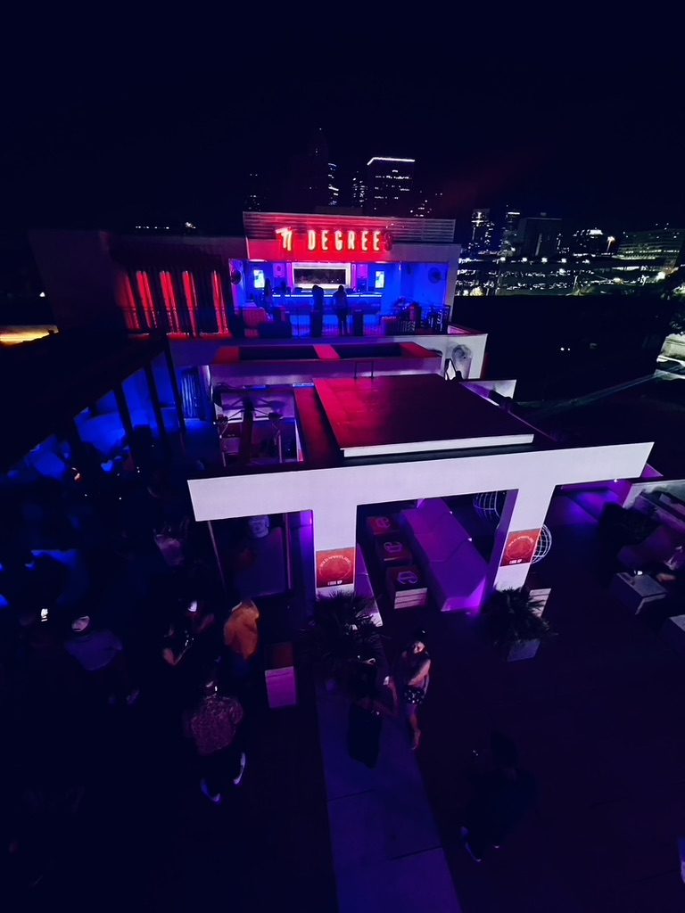 Aerial night view of the 77 Degrees rooftop lit in red and purple during the event