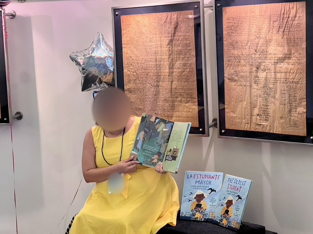 Story reading of The Oldest Student in front of framed historic documents, reader's face blurred